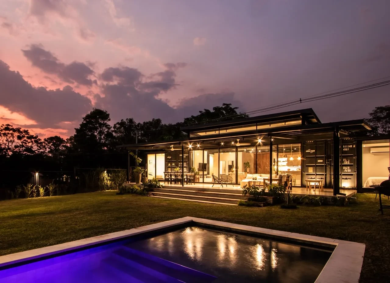 Vivienda de lujo construida con contenedores marítimos por Multitainer, al atardecer con piscina