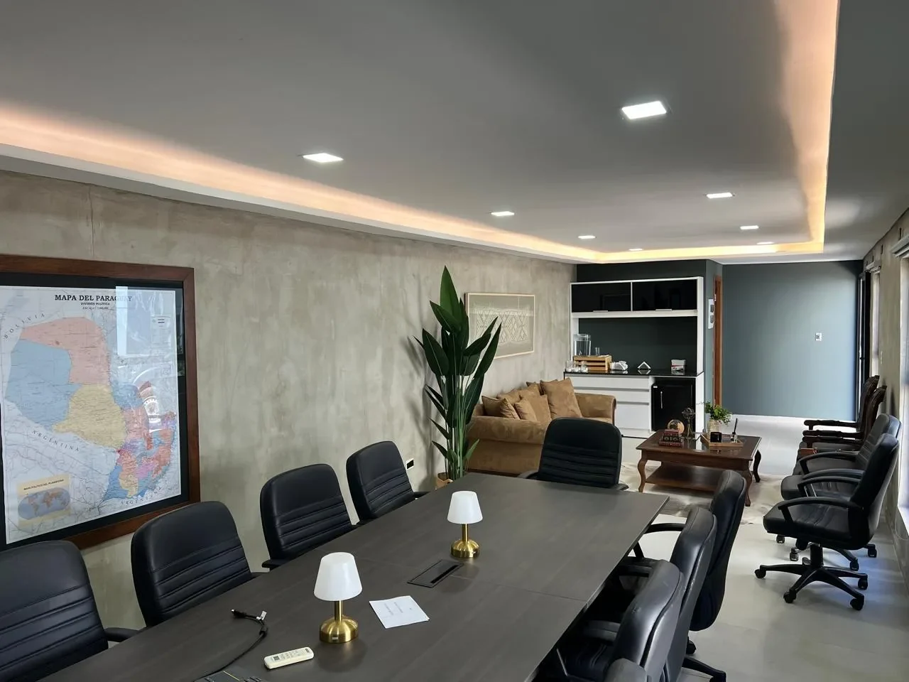 Oficina ejecutiva premium en contenedor con mesa de directorio, mapa del Paraguay enmarcado, microcemento, kitchenette y sofa de terciopelo.