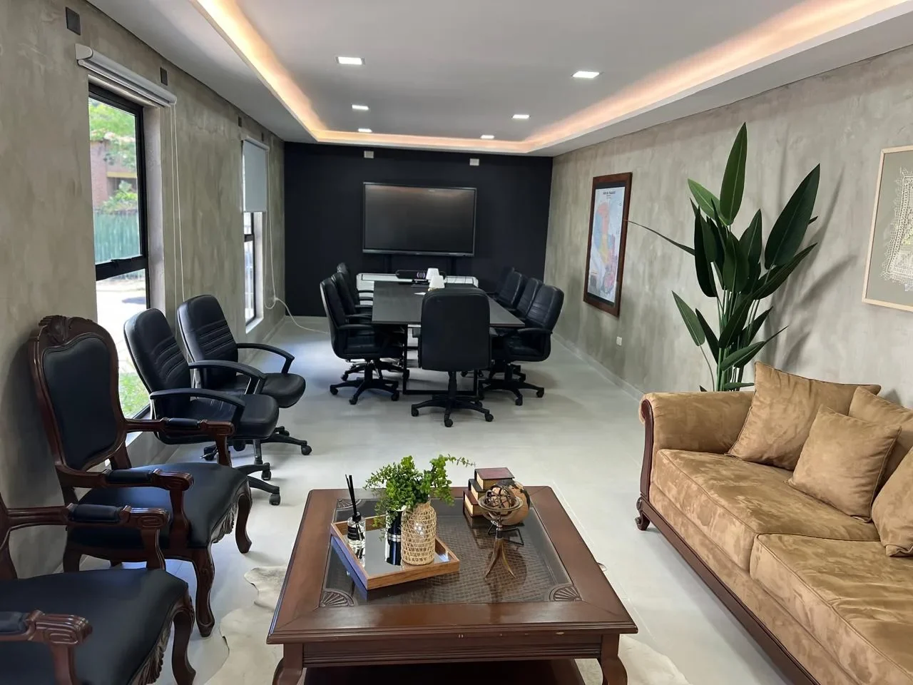 Oficina ejecutiva premium en contenedor con sala de directorio, microcemento, sofa de terciopelo dorado, mapa del Paraguay y pantalla.